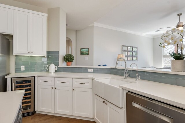 kitchen featuring tasteful backsplash, light countertops, white cabinets, beverage cooler, and dishwasher