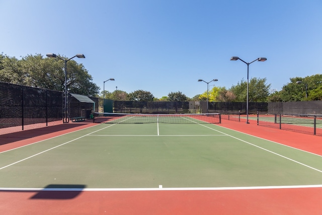 view of tennis court with community basketball court and fence