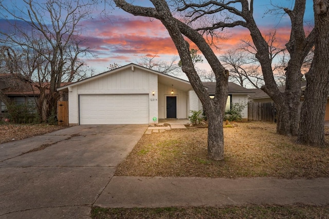 mid-century home featuring a garage, concrete driveway, brick siding, and fence