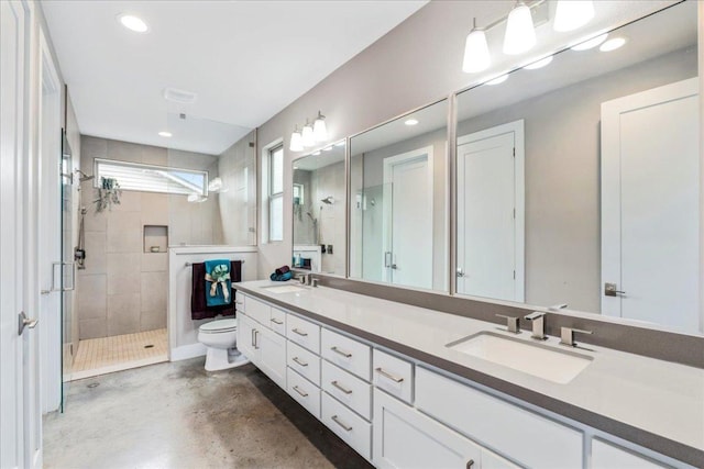 bathroom featuring double vanity, a stall shower, a sink, and toilet