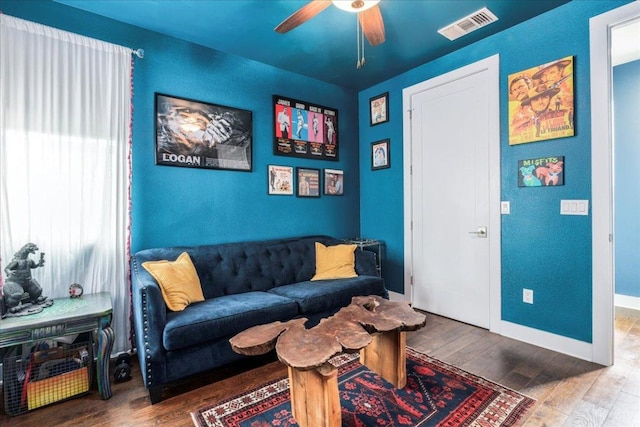 living area featuring baseboards, visible vents, ceiling fan, and hardwood / wood-style floors