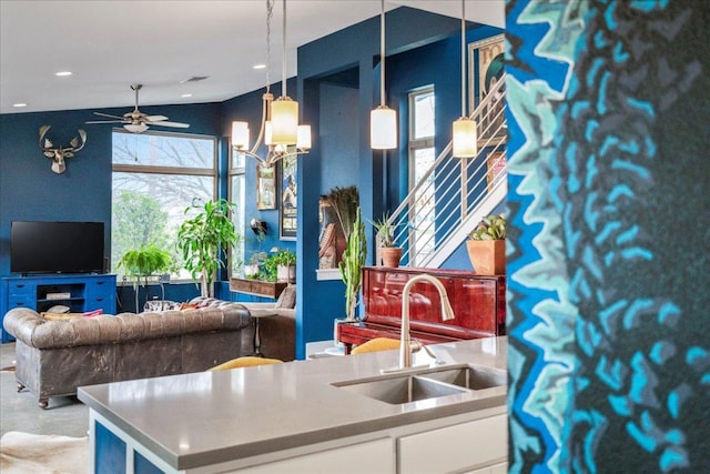 interior space featuring a sink, white cabinetry, a ceiling fan, open floor plan, and hanging light fixtures