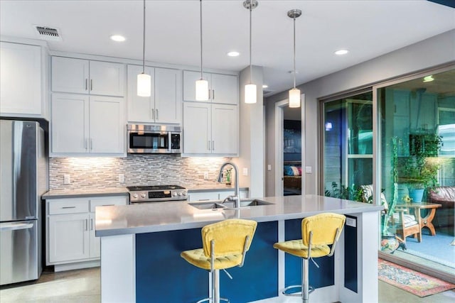 kitchen with appliances with stainless steel finishes, light countertops, a sink, and tasteful backsplash