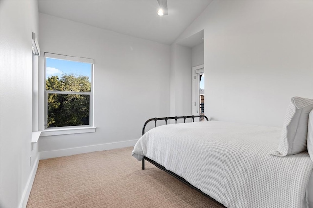 carpeted bedroom with lofted ceiling and baseboards