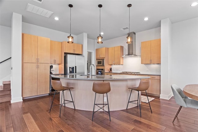 kitchen featuring a sink, visible vents, appliances with stainless steel finishes, dark wood-style floors, and wall chimney exhaust hood