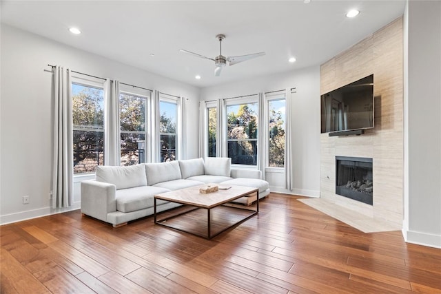 unfurnished living room featuring recessed lighting, ceiling fan, wood finished floors, a tile fireplace, and baseboards