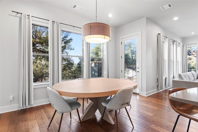 dining room with hardwood / wood-style floors, visible vents, and a healthy amount of sunlight