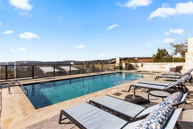 community pool with a patio area and fence