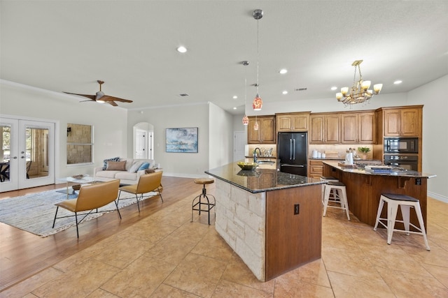 kitchen with arched walkways, a spacious island, decorative backsplash, black appliances, and a kitchen breakfast bar