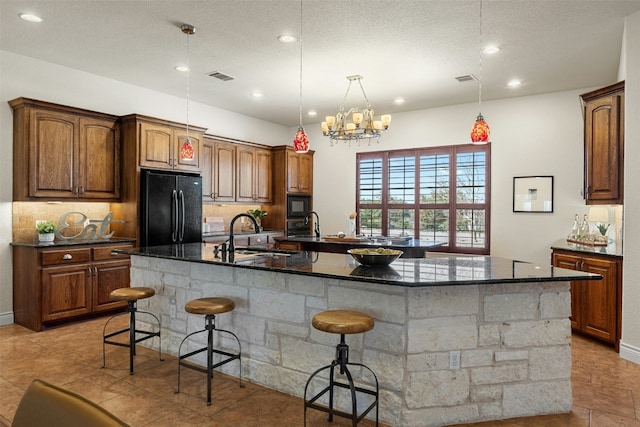 kitchen featuring visible vents, a spacious island, black appliances, a kitchen bar, and a sink