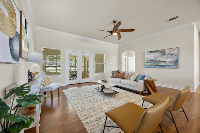 living area featuring arched walkways, french doors, visible vents, and wood finished floors