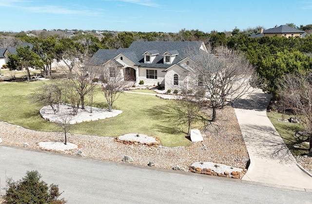 view of front of house with stone siding, a front lawn, and concrete driveway