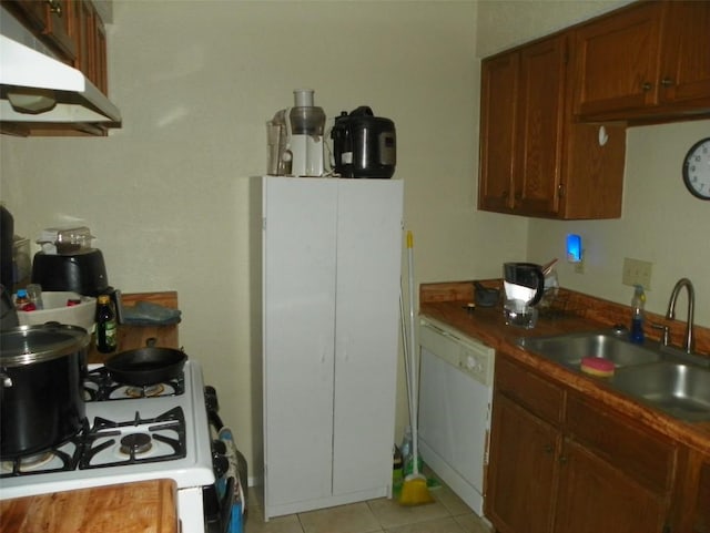 kitchen featuring light tile patterned floors, brown cabinetry, a sink, white appliances, and under cabinet range hood