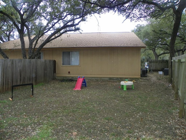 rear view of property featuring roof with shingles and fence