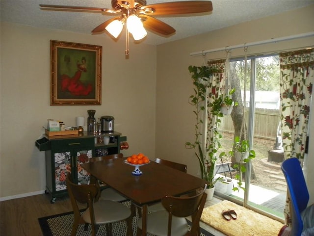 dining space with a textured ceiling, baseboards, and wood finished floors