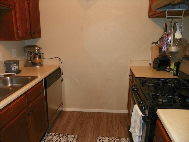 kitchen with dishwasher, light countertops, wood finished floors, and black gas stove