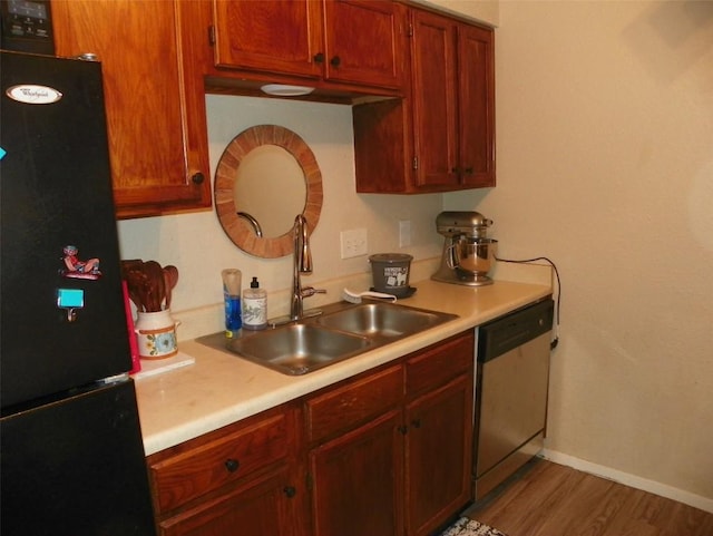 kitchen with a sink, light countertops, stainless steel dishwasher, and freestanding refrigerator