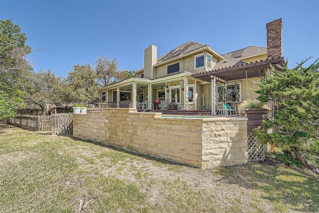 rear view of house with a patio area, a lawn, a chimney, and fence