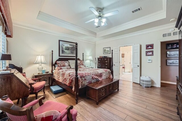 bedroom with baseboards, visible vents, light wood finished floors, ornamental molding, and a raised ceiling