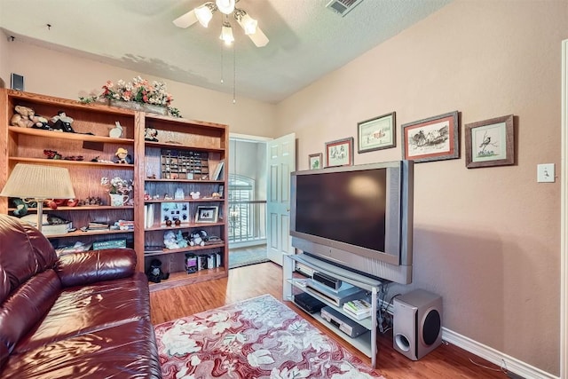 living room with visible vents, baseboards, wood finished floors, and a ceiling fan