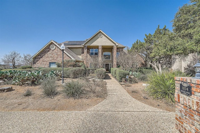 view of front of home featuring roof mounted solar panels and brick siding