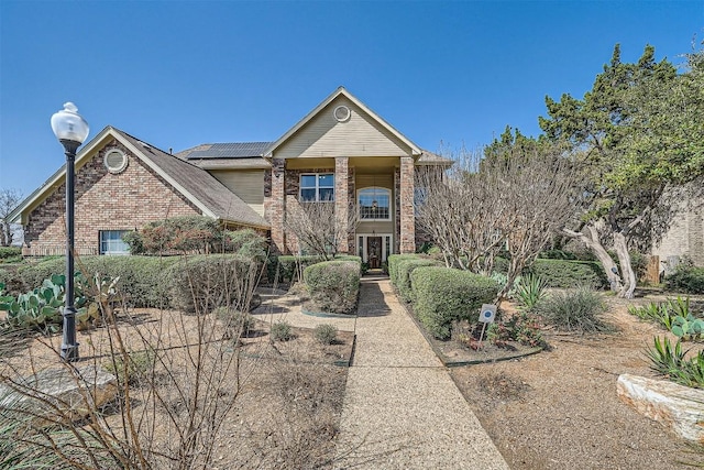 view of front of house featuring brick siding and roof mounted solar panels