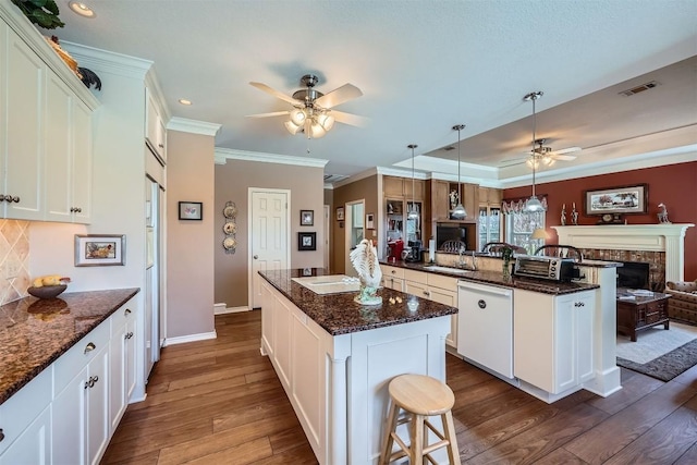 kitchen featuring visible vents, a kitchen island, dark wood finished floors, dishwasher, and open floor plan