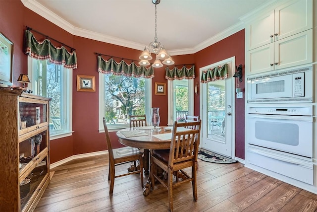 dining space featuring baseboards, an inviting chandelier, crown molding, and light wood finished floors