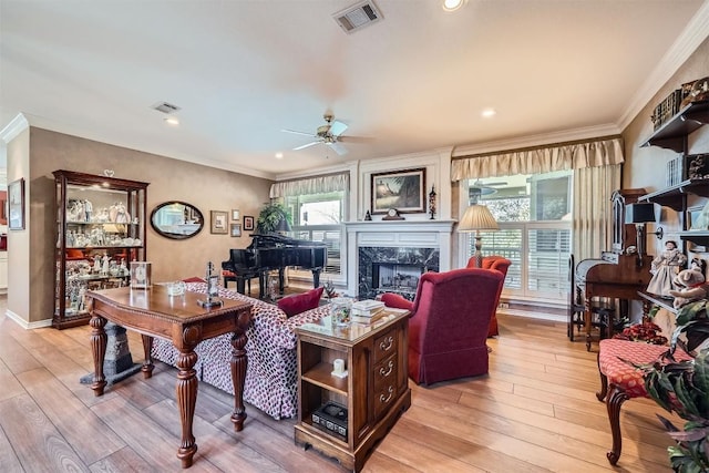 living area with light wood-style flooring, visible vents, a high end fireplace, and ornamental molding