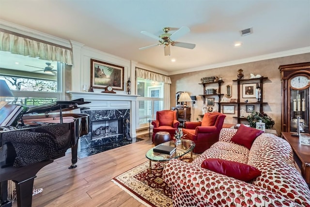 living room with wood finished floors, visible vents, a premium fireplace, ceiling fan, and crown molding