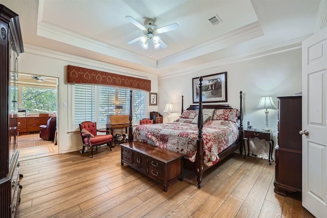 bedroom featuring light wood-style floors, a tray ceiling, and ornamental molding