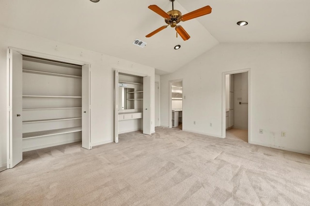 unfurnished bedroom with multiple closets, light colored carpet, visible vents, connected bathroom, and vaulted ceiling