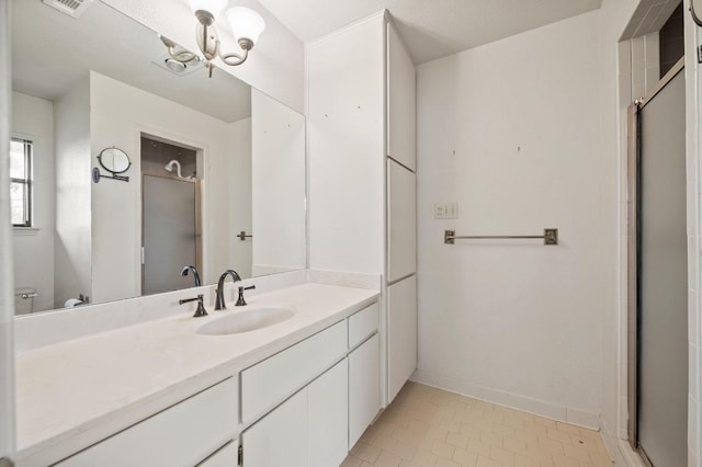 bathroom with a notable chandelier, vanity, baseboards, tile patterned floors, and a shower with door