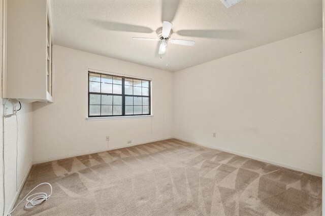 spare room with light carpet, a textured ceiling, and a ceiling fan