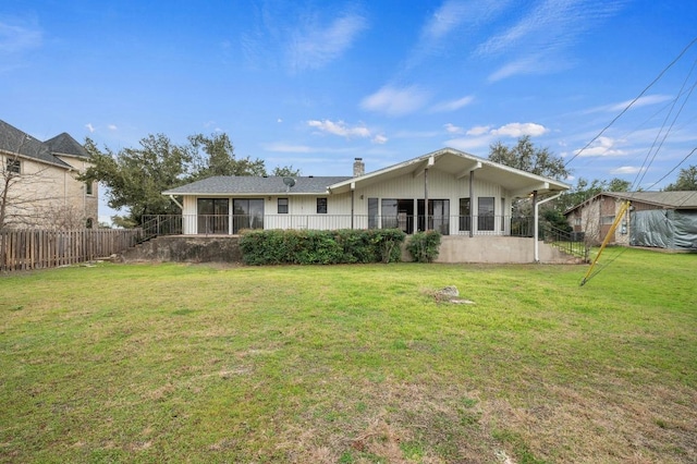 rear view of property with a yard, a chimney, and fence