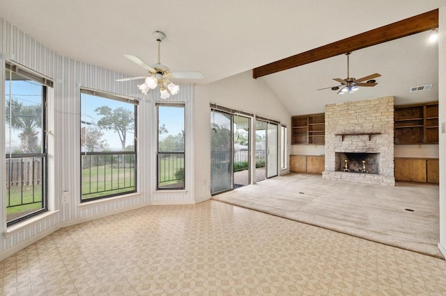 unfurnished living room featuring a healthy amount of sunlight, visible vents, beamed ceiling, and a stone fireplace