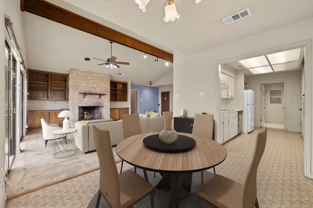 dining area with vaulted ceiling with beams, ceiling fan, a fireplace, and visible vents