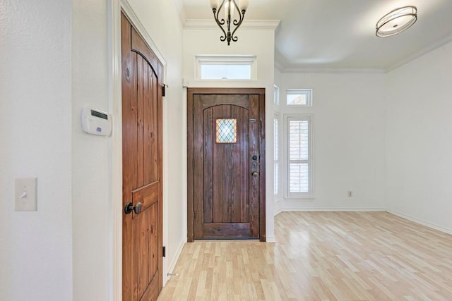 foyer entrance featuring ornamental molding, light wood-type flooring, and baseboards