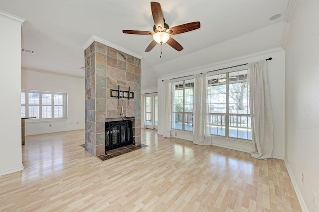 unfurnished living room featuring baseboards, a ceiling fan, a tiled fireplace, wood finished floors, and crown molding