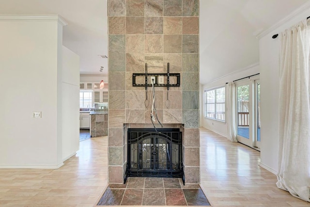 living room featuring a tile fireplace, a high ceiling, light wood-style flooring, and baseboards