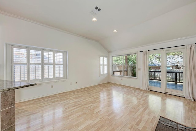 unfurnished living room with light wood-style floors, plenty of natural light, and vaulted ceiling