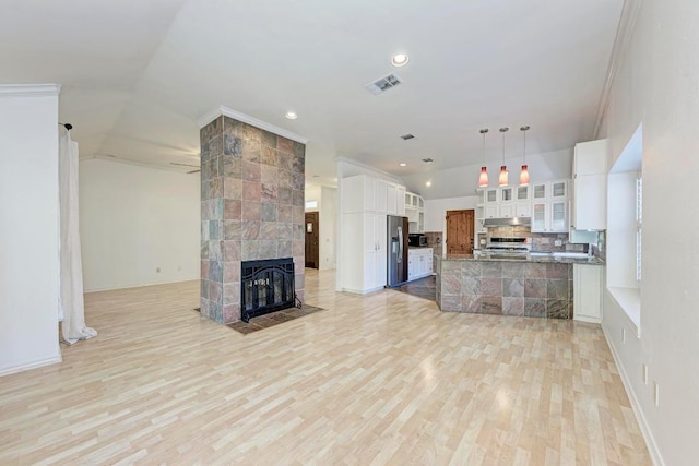 kitchen with lofted ceiling, visible vents, open floor plan, a tile fireplace, and stainless steel fridge with ice dispenser