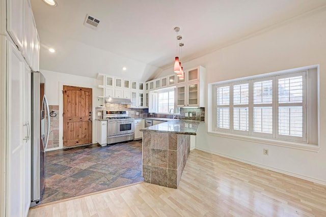 kitchen featuring stainless steel stove, under cabinet range hood, a peninsula, visible vents, and white cabinetry