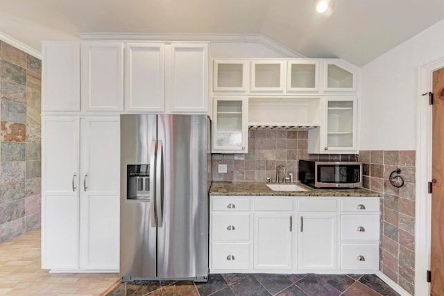 kitchen featuring a sink, white cabinetry, appliances with stainless steel finishes, dark stone countertops, and glass insert cabinets