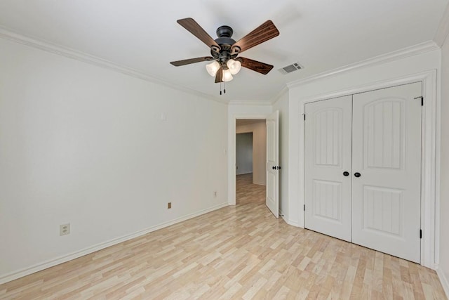 unfurnished bedroom featuring a closet, visible vents, light wood-style floors, ornamental molding, and baseboards