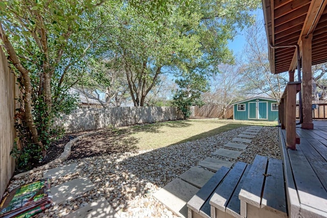 view of yard with a fenced backyard, a wooden deck, and an outbuilding