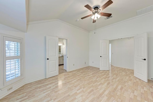 unfurnished bedroom featuring light wood finished floors, visible vents, vaulted ceiling, and crown molding