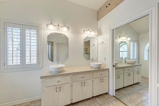 full bath with a sink, baseboards, and double vanity