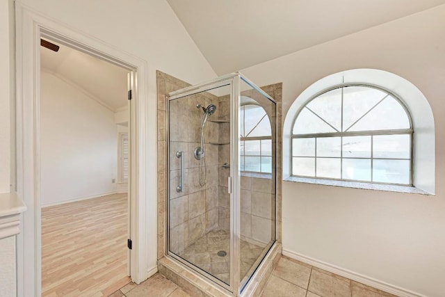 bathroom with vaulted ceiling, baseboards, a shower stall, and tile patterned floors