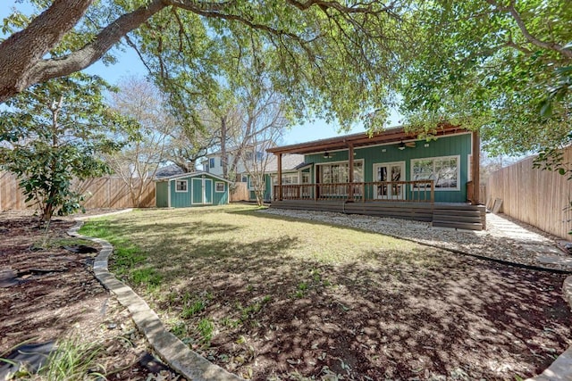 view of yard with an outbuilding, ceiling fan, a shed, and a fenced backyard